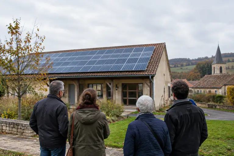 Habitants observant des panneaux solaires sur un bâtiment public en milieu rural français