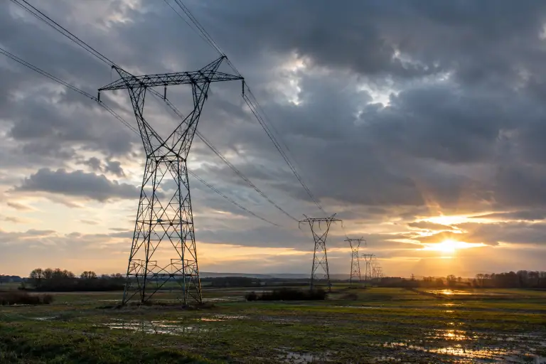 Des pylônes traversent une plaine française sous un ciel d’hiver chargé.